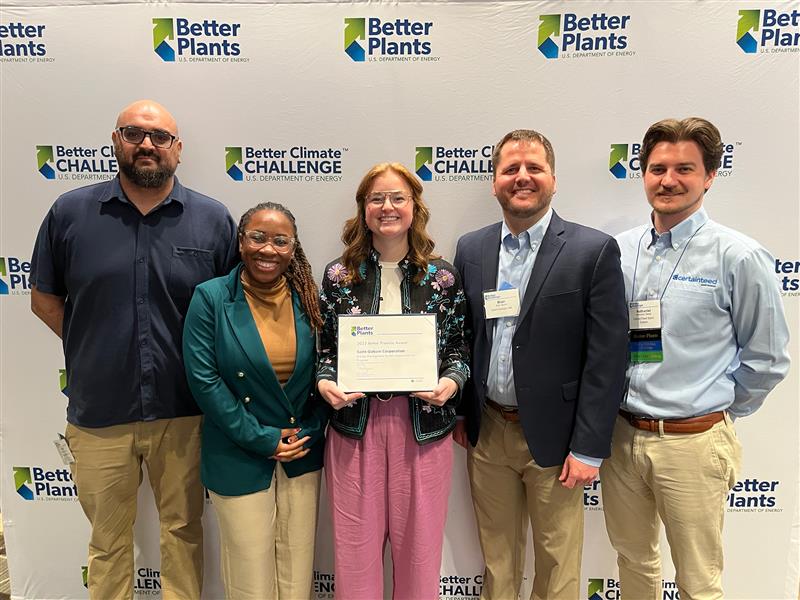 /Five%20employees%20are%20standing%20in%20from%20of%20a%20banner%20that%20says%20%22Better%20Plants%2C%20Better%20Climate%20Challenge%22%20holding%20an%20award