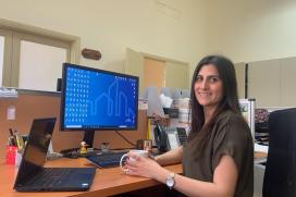 A woman employee sits at her desk holding a coffee mug. 