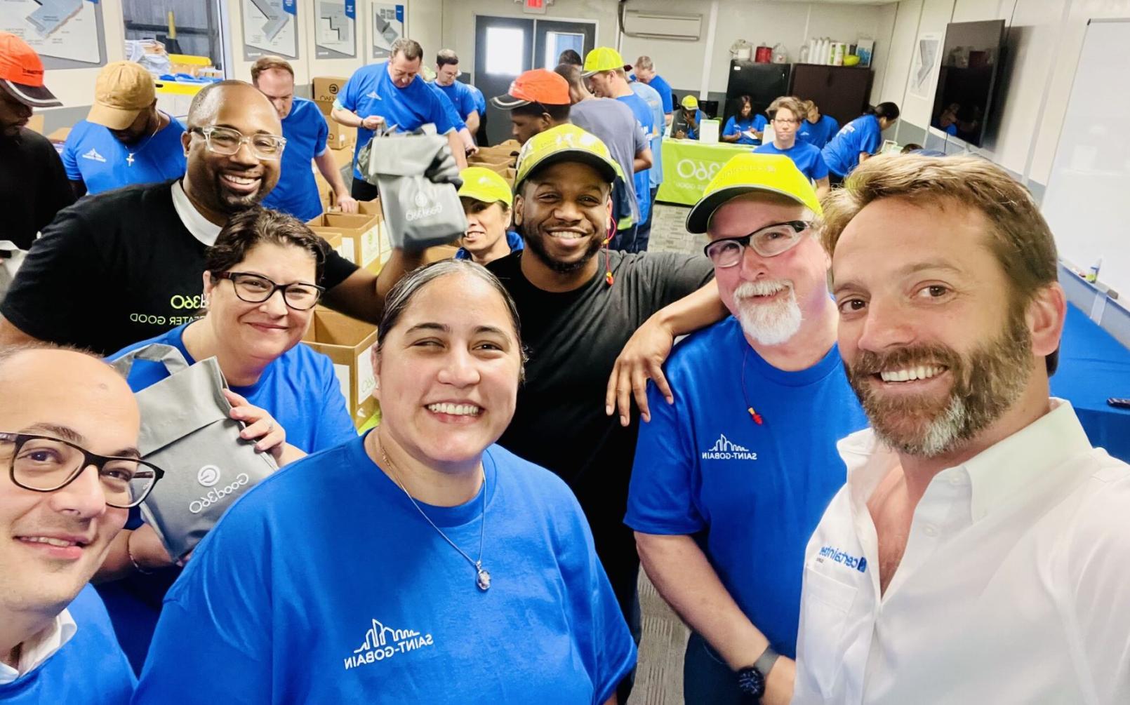 A selfie-style picture with a large group wearing blue company t-shirts at a volunteer event