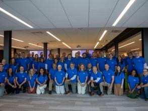 A large group of people wearing matching tshirts are posed for a photo