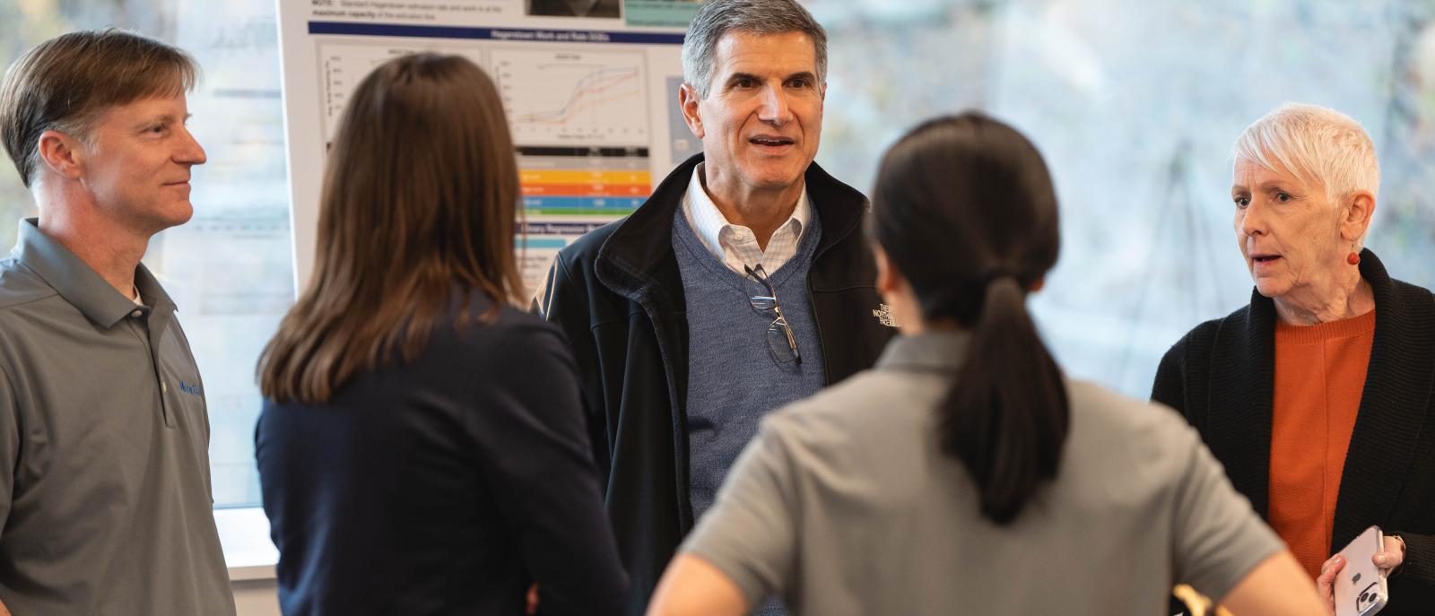 Group of five people gathered in front of a poster presentation display.