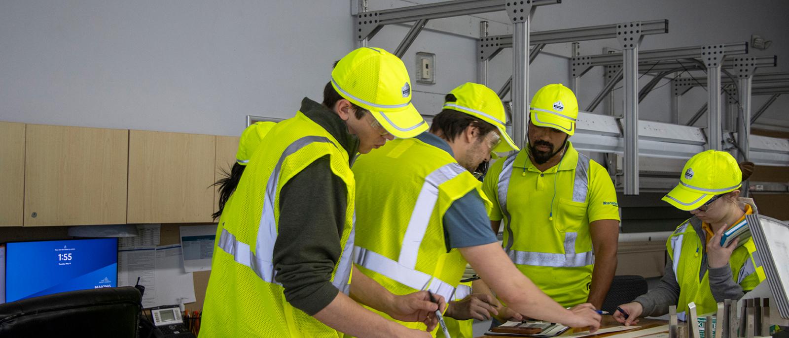 Four engineers wearing safety gear are gaining valuable experience with the engineering development program called Essentials of Manufacturing