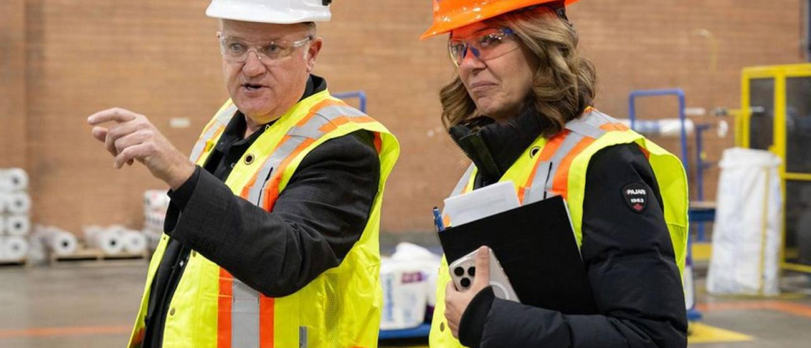 Professionals in safety gear discussing a key part of Essentials of Sales and manufacturing jobs at a Saint-Gobain production facility.