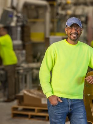 A male employee at a Saint-Gobain North America plant smiles, proud of his successful path in manufacturing and operations jobs.